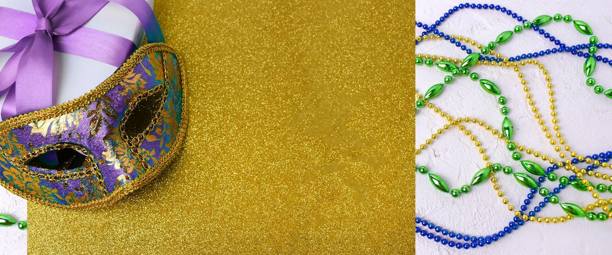 Una maschera viola e dorata, un regalo con un nastro viola, e colorate collane di perline.