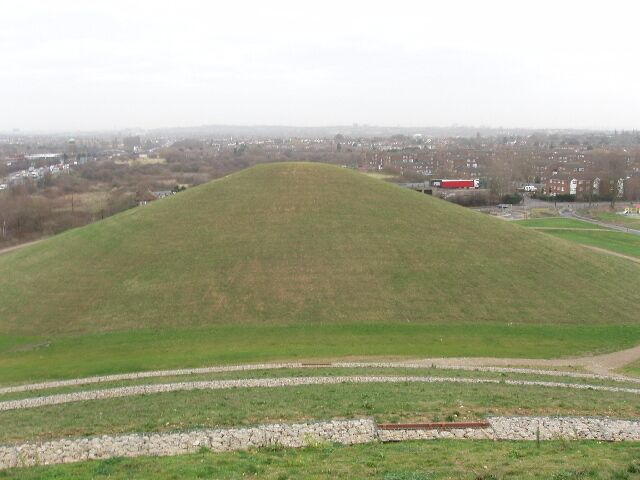 Northala Fields mound viewed from another mound. Two of the conical mounds at Northala fields are available for the public to view. For a photo in June 2005 when the project started see 17543. By November 2006 some of the mounds had taken shape (see 275147), filled with demolition material from Wembley Stadium and White City. The photograph is taken from the biggest mound which has a gently rising spiral walkway to the top. Three turns of the spiral can be seen in the foreground. Beyond is a grassy mound open to the public but with no marked path.
