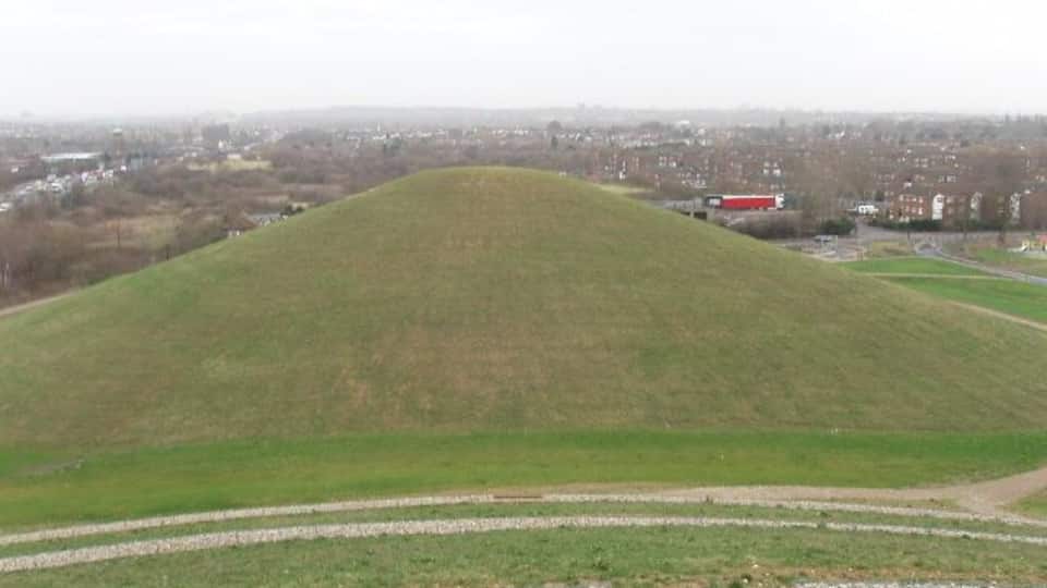 A large grassy hill with a road leading up to it.