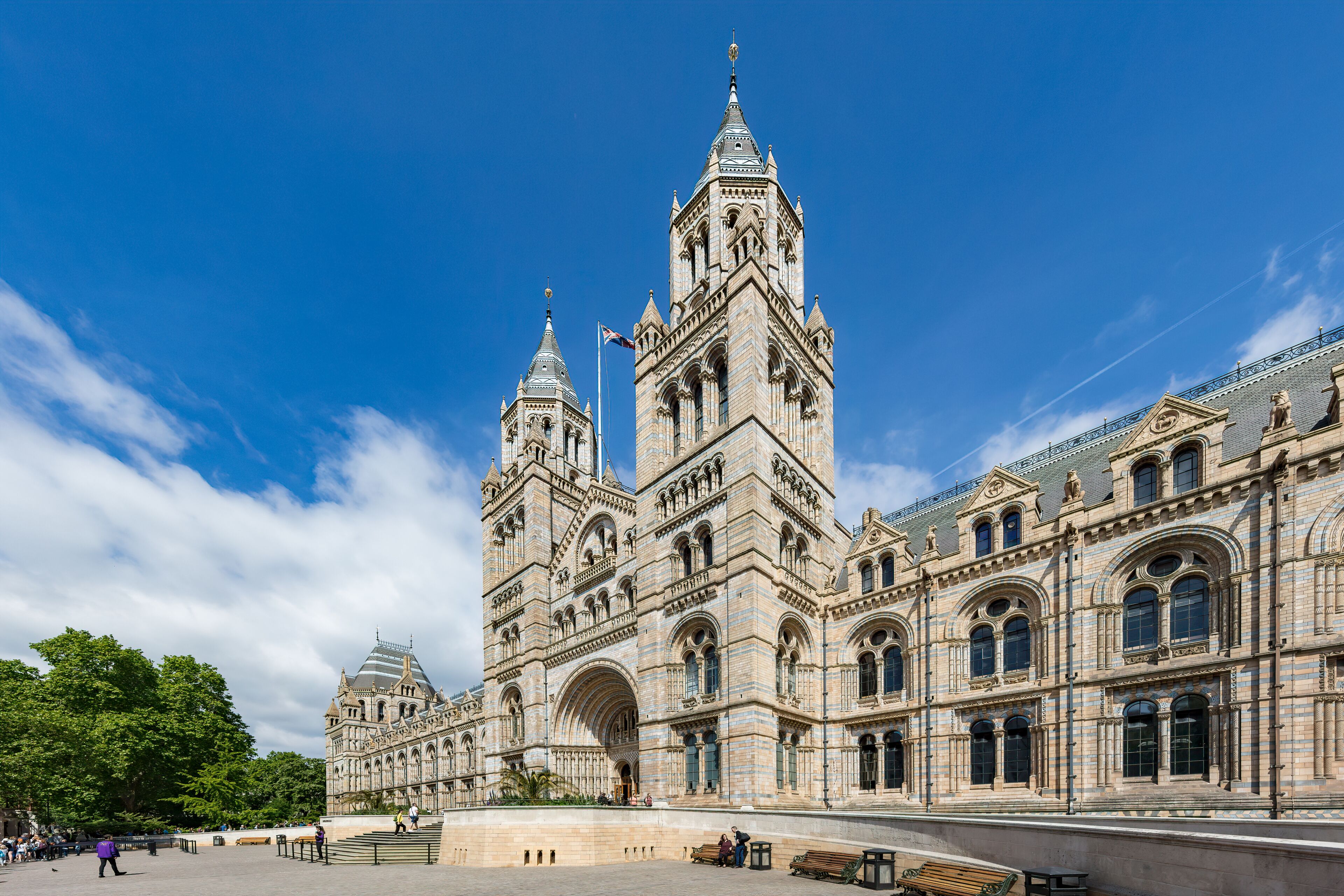 A grand historic building with two prominent towers, a large arched entrance, and a spacious plaza.