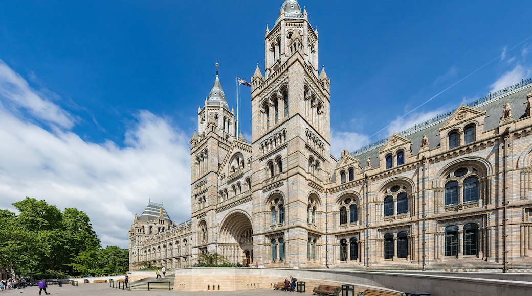 A grand historic building with two prominent towers, a large arched entrance, and a spacious plaza.