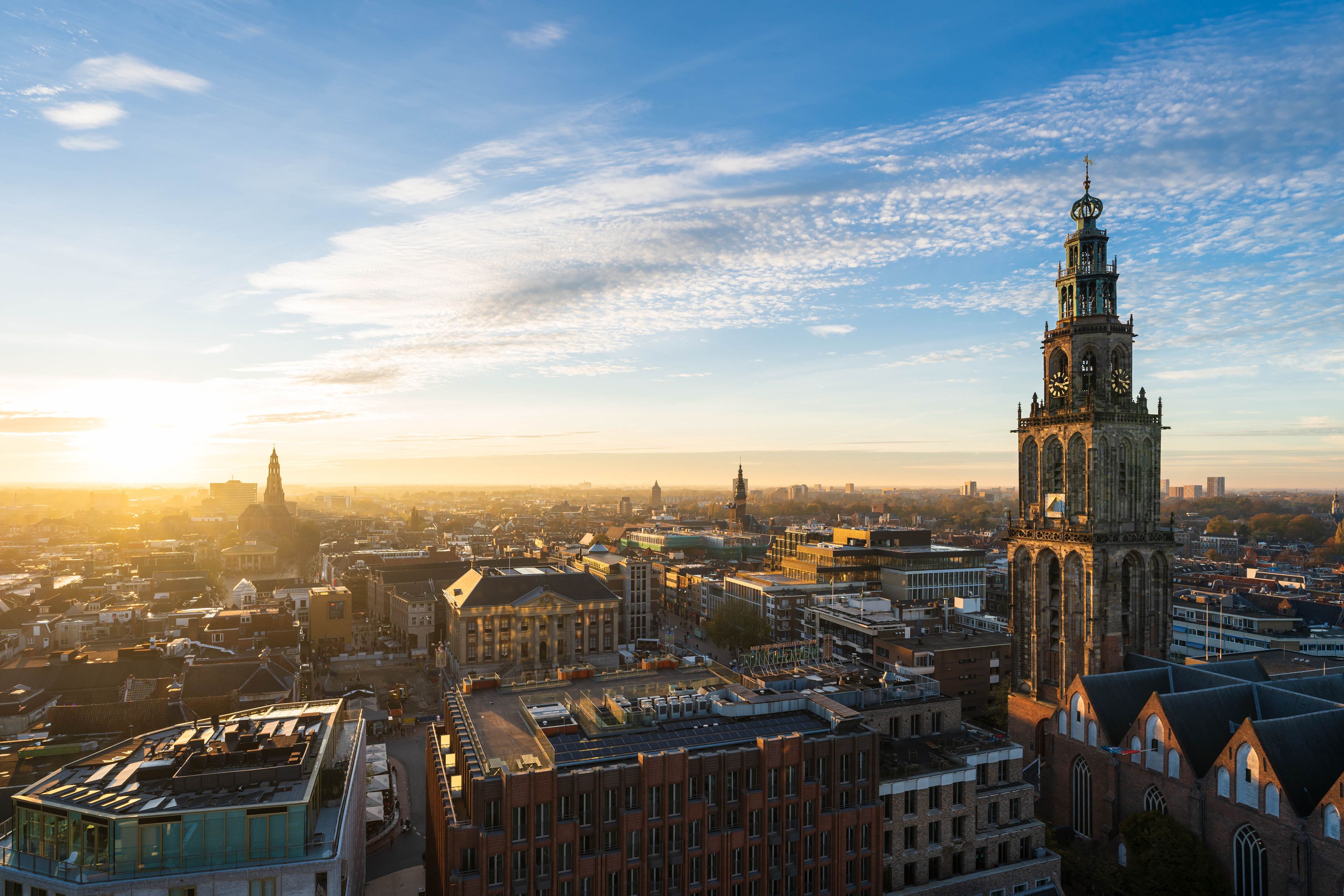 A cityscape with a prominent historic tower and a modern building with a glass facade.
