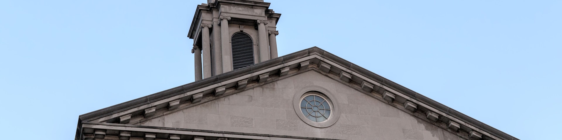A classical building with 'Midwood High School' inscribed on its facade, featuring a prominent clock tower and columns.