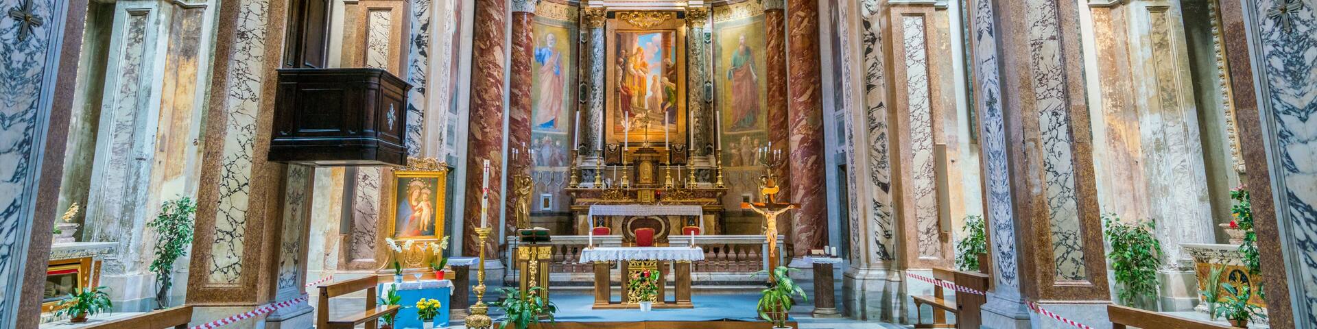 An ornate church interior with marble columns, a central altar, and religious paintings.
