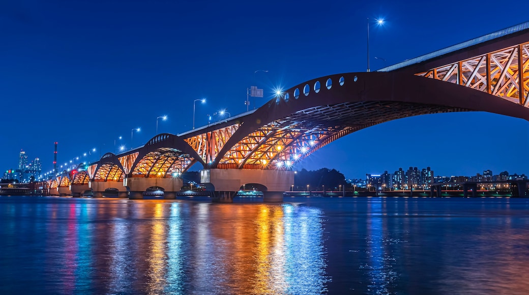 A brightly lit bridge at night with its reflection on the water.