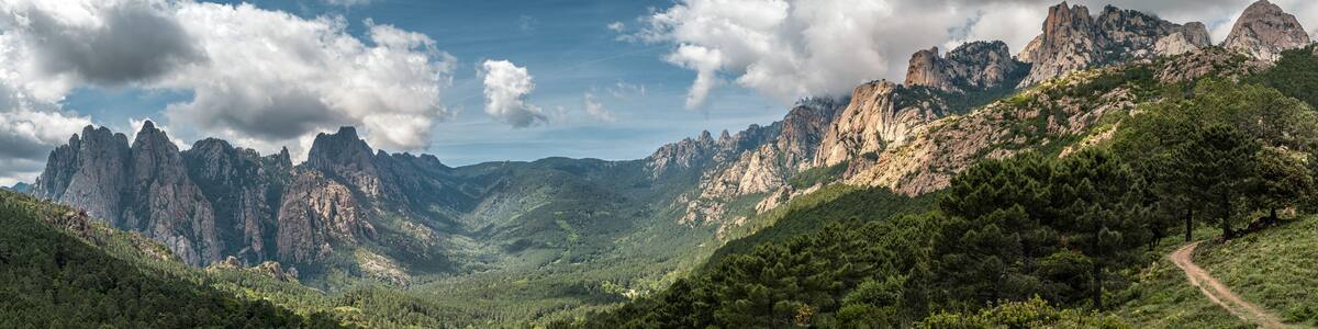 Panoramic view of the Aiguilles de Bavella, needle like rocky mountain peaks surrounded by pine forest and maquis in the centre of Corsica