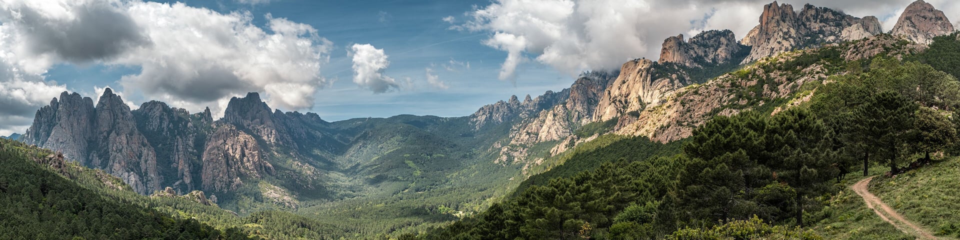 Panoramic view of the Aiguilles de Bavella, needle like rocky mountain peaks surrounded by pine forest and maquis in the centre of Corsica