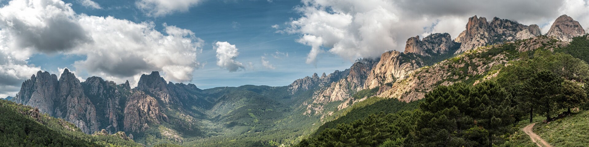A mountainous landscape with rugged peaks and dense forest.