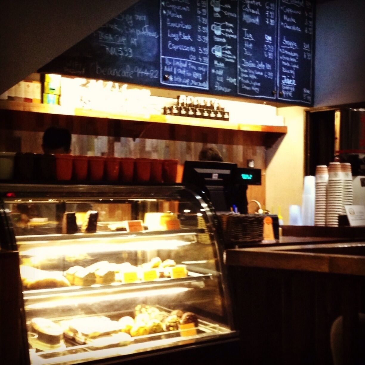 A bakery display case with pastries and a chalkboard menu above.