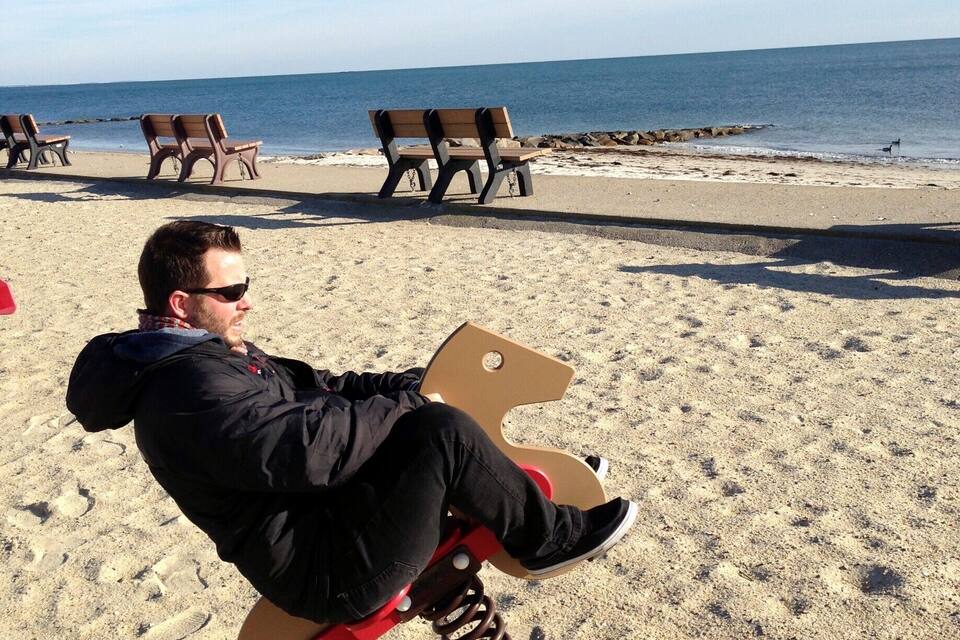 Una persona asseguda en una cadira a la platja sorrenca, amb l'oceà de fons.