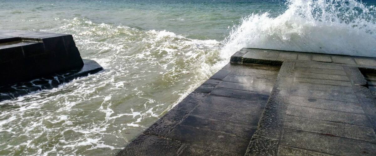 A concrete pier with waves crashing against it.