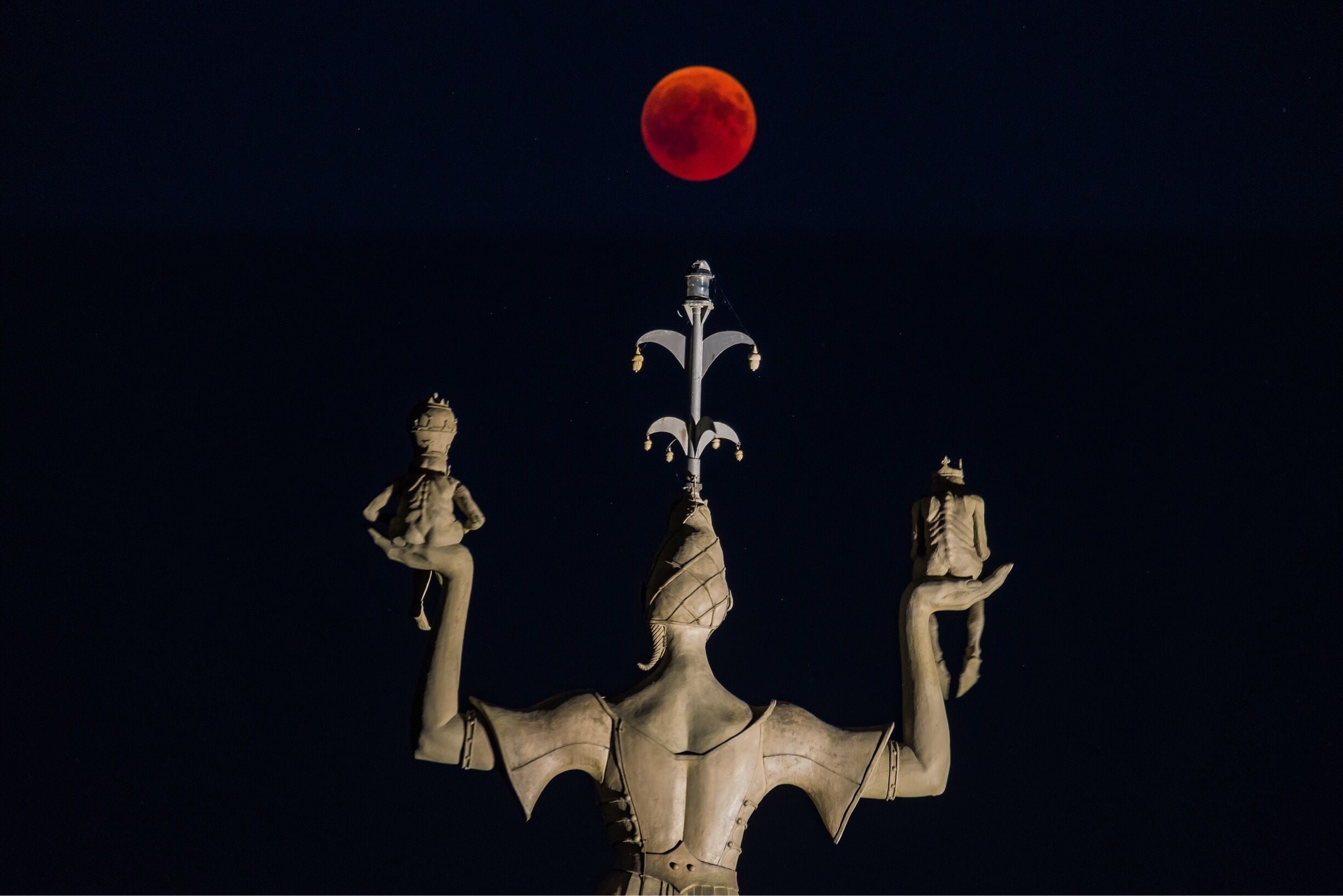 Imperia is a statue by Peter Lenk in the harbour of Konstanz. She is 9m high, weights 18 tons and turns on its axis every 4 minutes. 
Her location in the harbour makes it possible to integrate her into compositions of lunar eclipses ( such as the one of July 27 2018 in this case). 
Very popular spot #LikeALocal