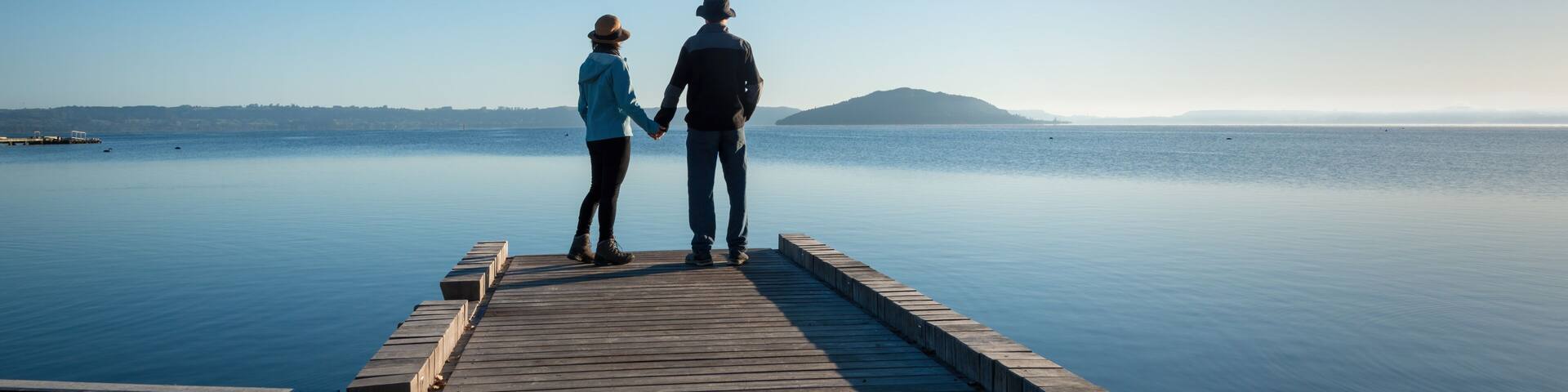 Couple holding hands, standing on the lakefront boardwalk, Rotorua.