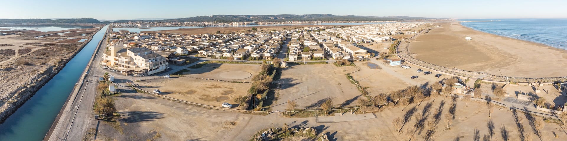 An aerial view of a coastal town with a river, beach, and residential area.