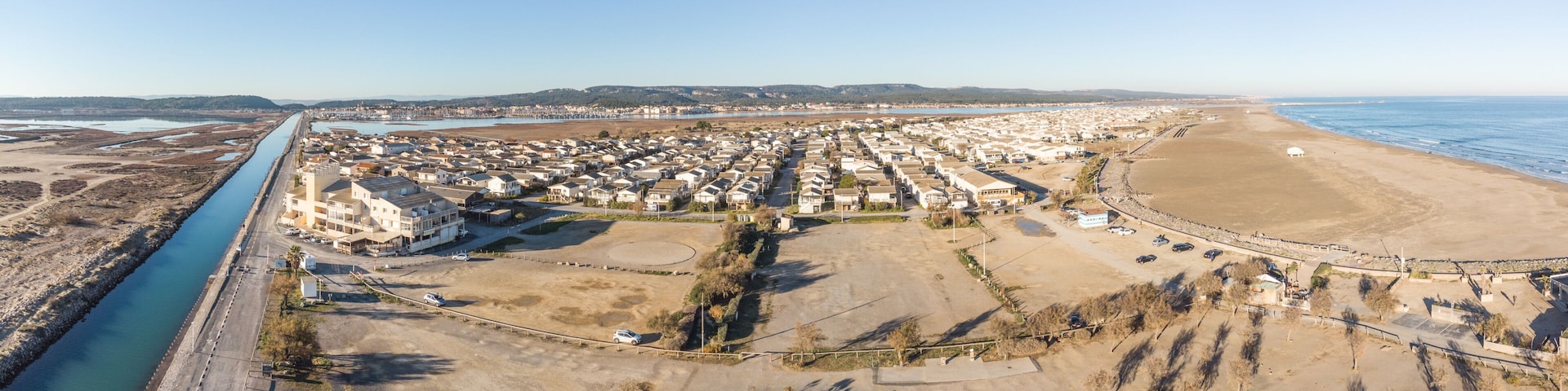 Vue aĂ©rienne dâune ville cĂŽtiĂšre avec une riviĂšre, une plage et un quartier rĂ©sidentiel.