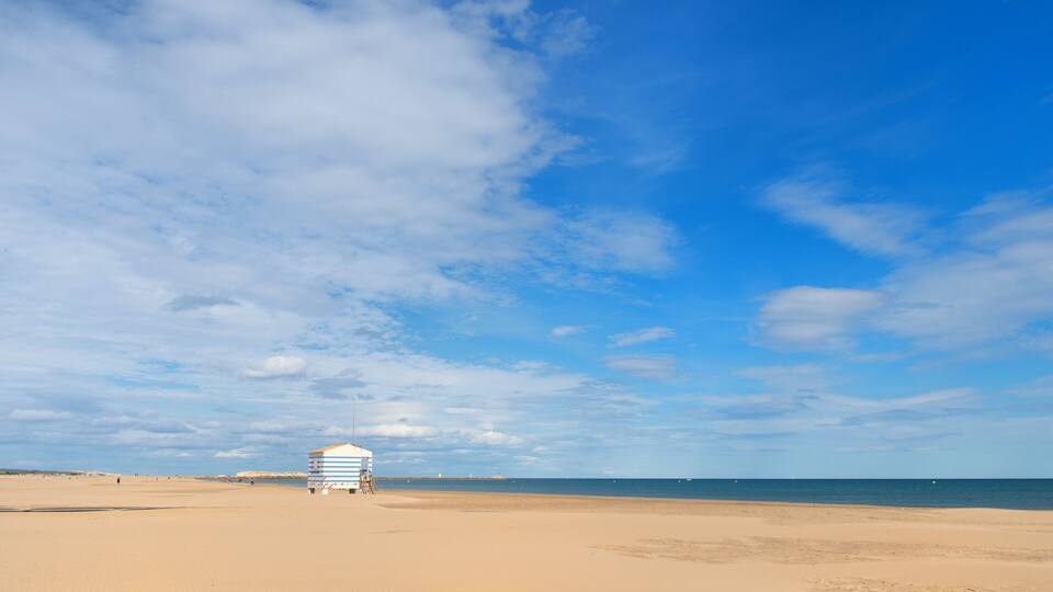 A beach with a lifeguard tower and a clear blue sky.