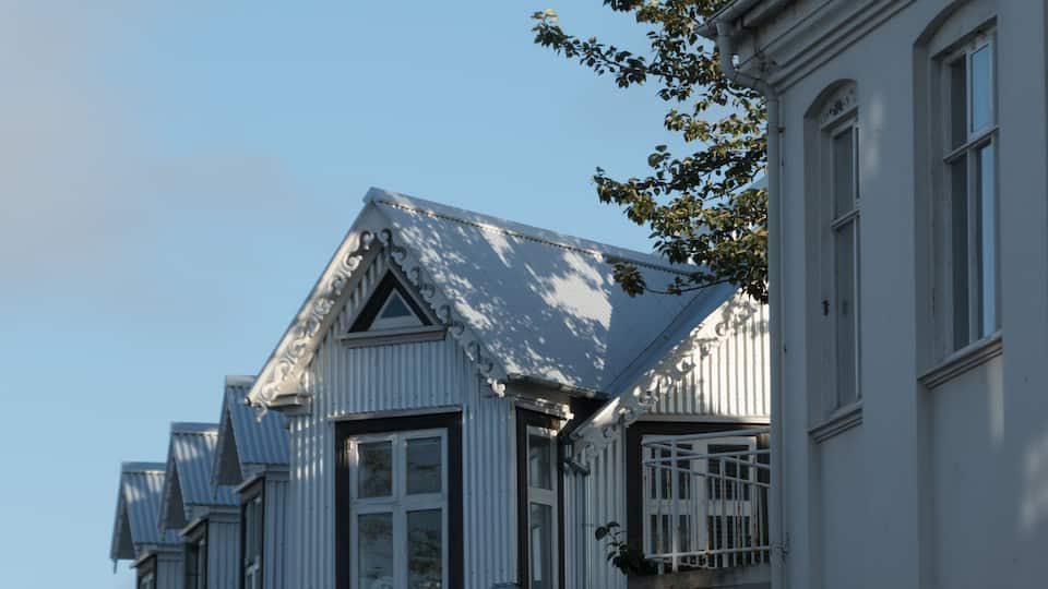 Row of traditional white painted houses in northern part of downtown, with sun highlights and wooded ornament details in exterior