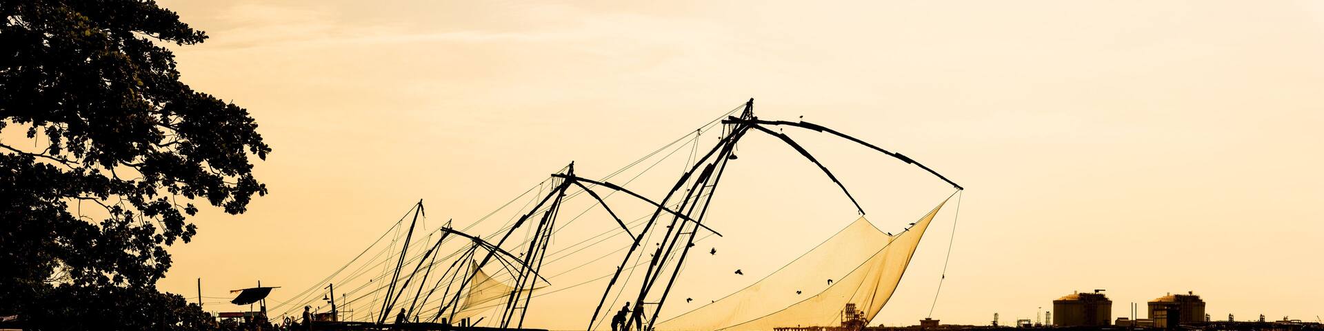 Panoramic silhouette of chinese fishnets on sunset at Fort Kochi, Kerala, India.