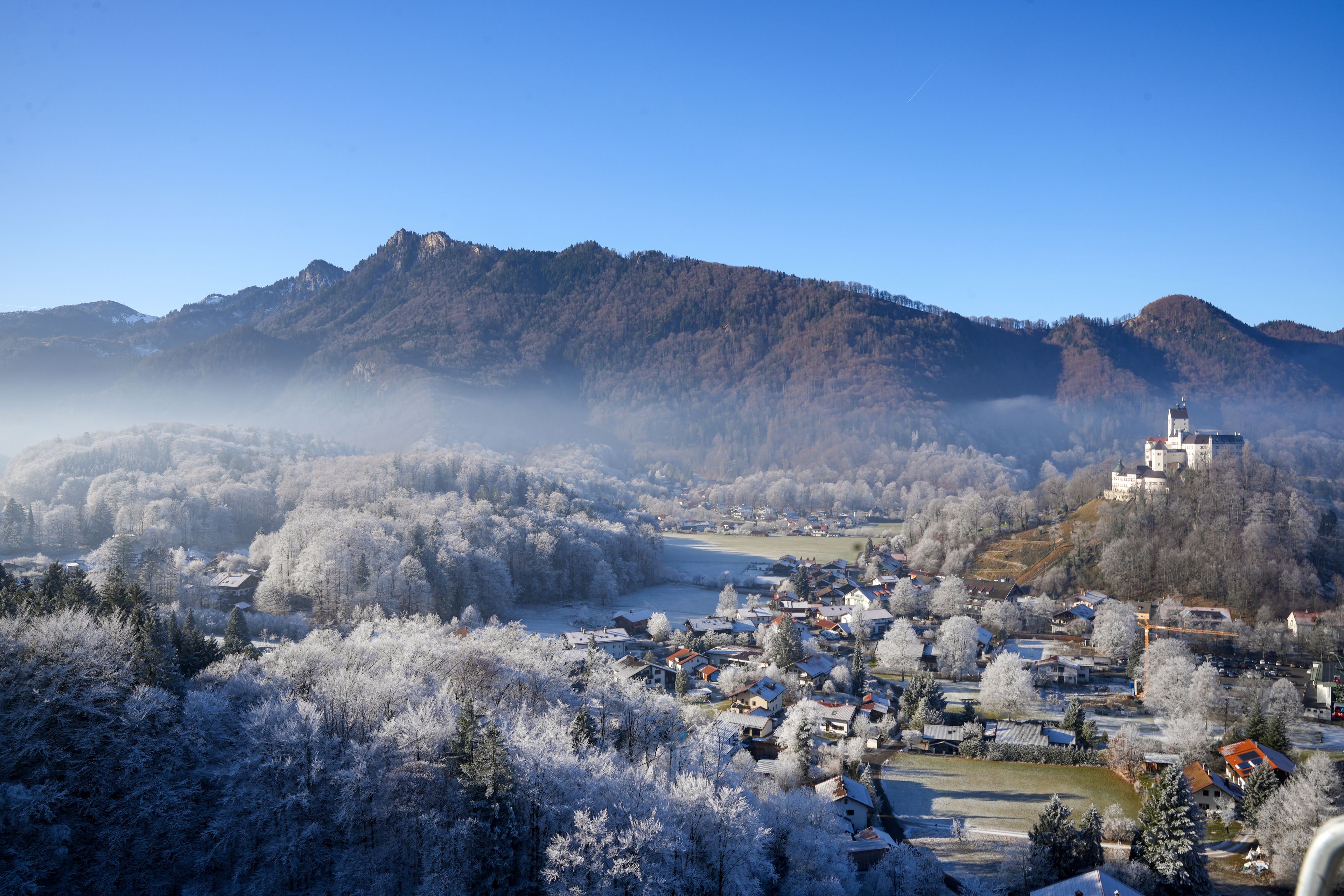 Un villaggio innevato con una chiesa e montagne sullo sfondo.