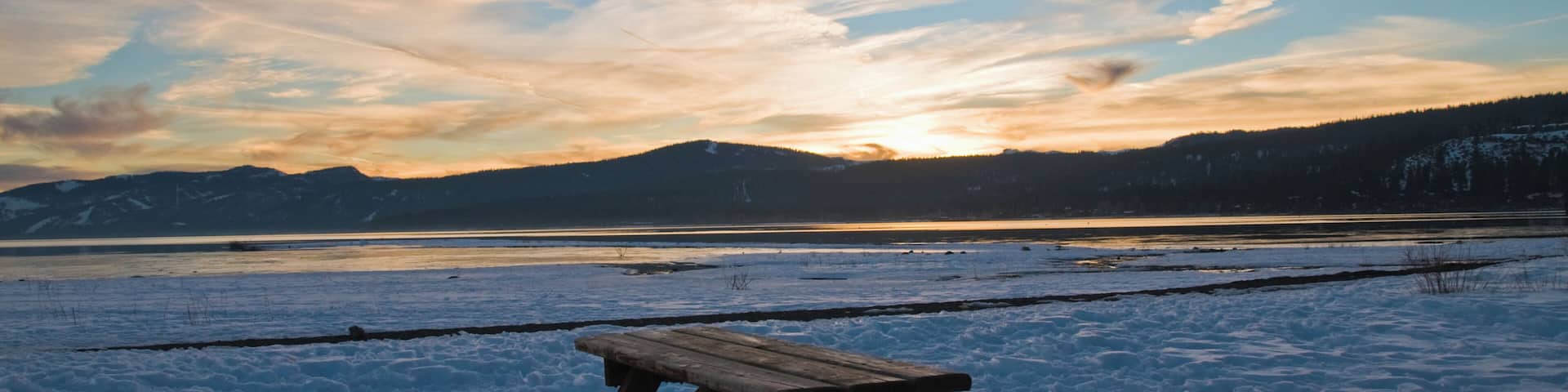 Picnic bench surrounded by snow at sunset in Lake Tahoe, California.