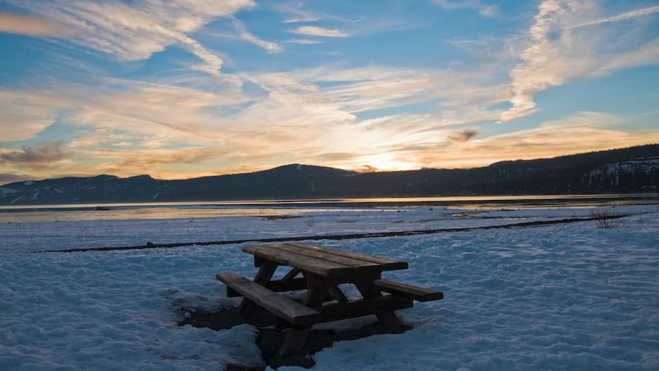 Picnic bench surrounded by snow at sunset in Lake Tahoe, California.