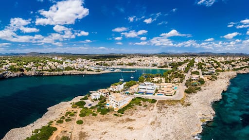 A coastal town with a marina, rocky coastline, and a clear blue sky.