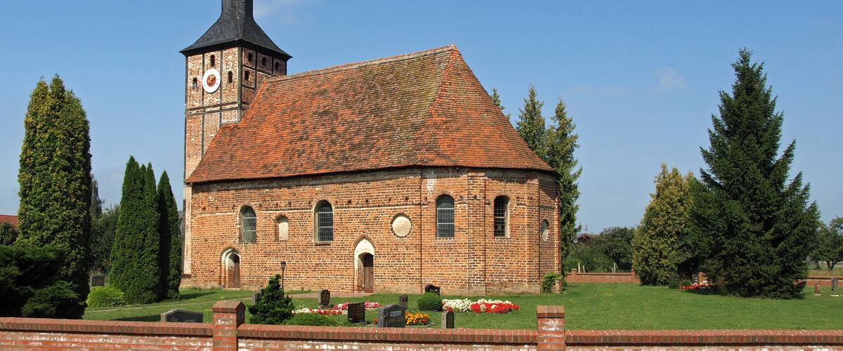 A brick church with a clock tower and a red-tiled roof.