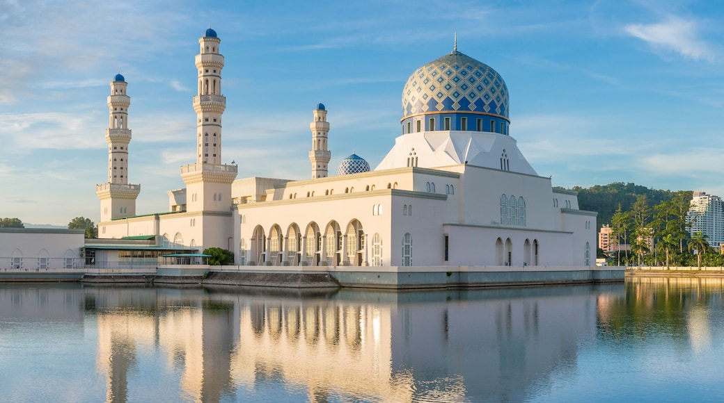 En moské med en stor kuppel og to minareter, der spejler sig i stille vand.