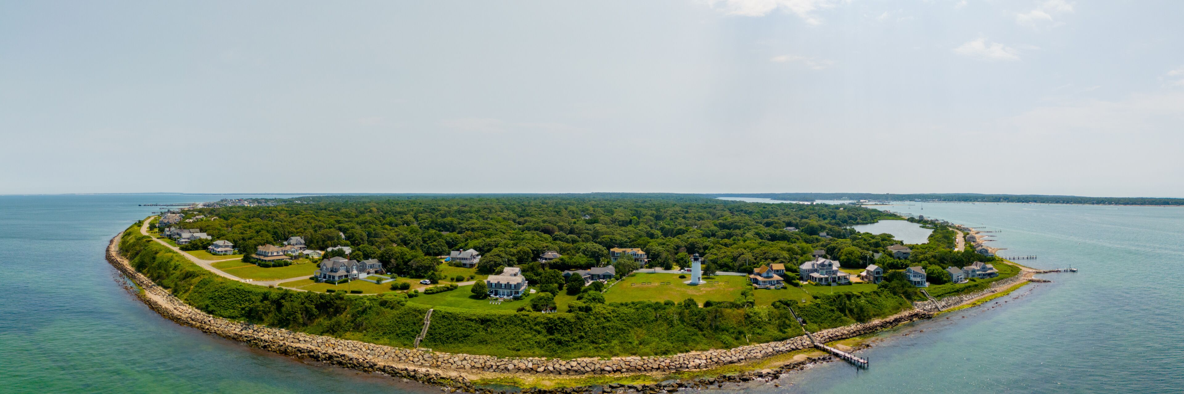 A coastal town with houses, a lighthouse, and a rocky shoreline.