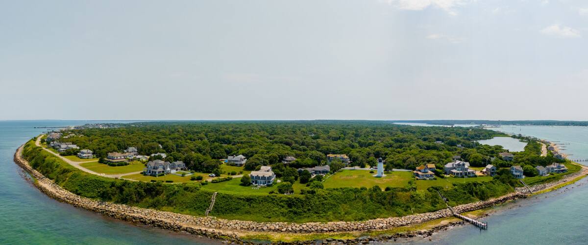 A coastal town with houses, a lighthouse, and a rocky shoreline.
