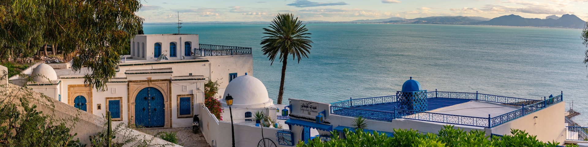 A coastal town with white buildings, blue doors, and a view of the sea.