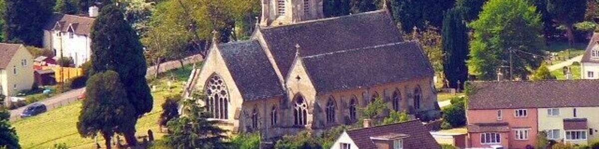 A church with a tall spire surrounded by lush greenery and residential houses.