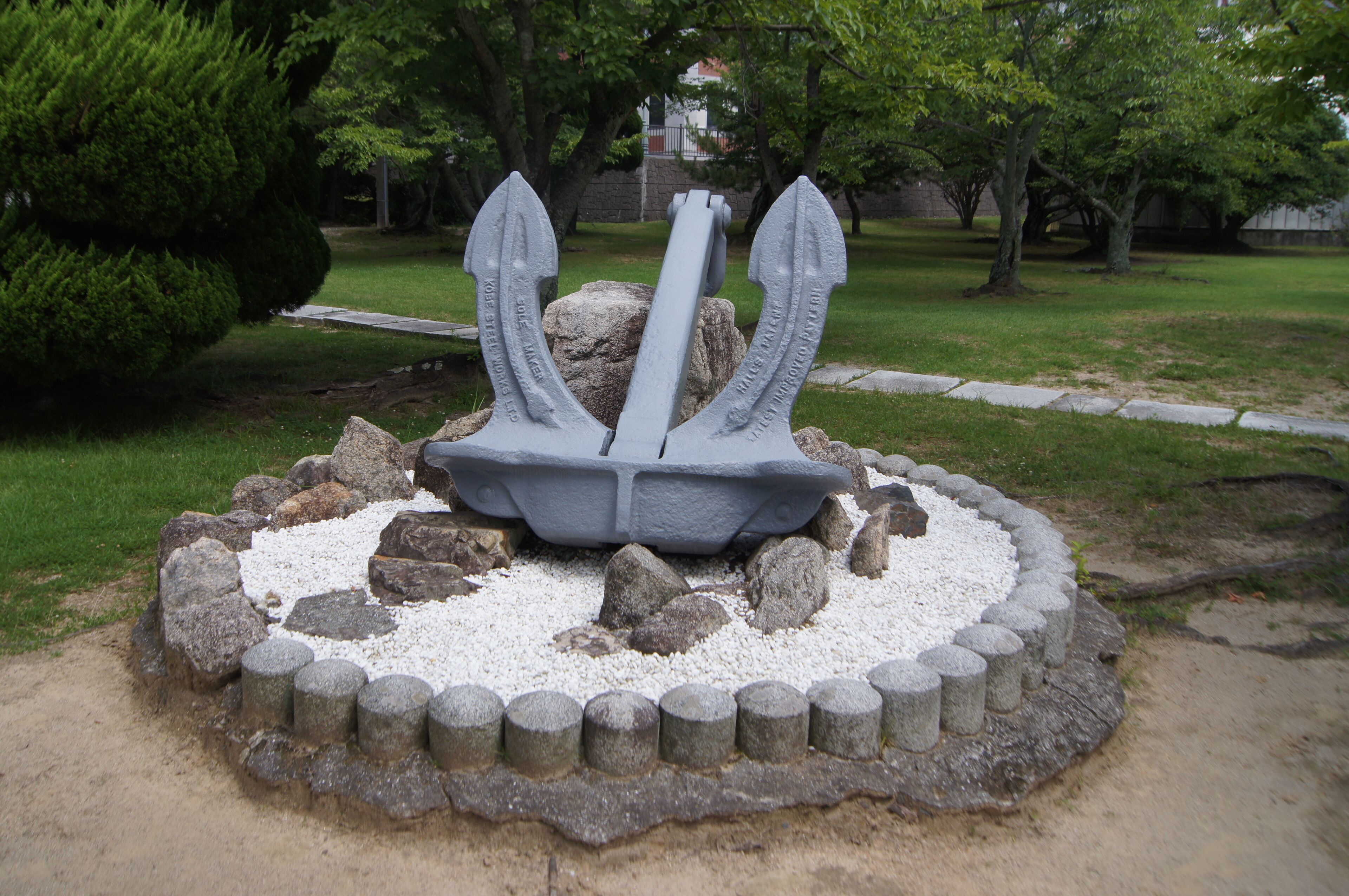 A stone sculpture of an anchor surrounded by rocks and gravel.