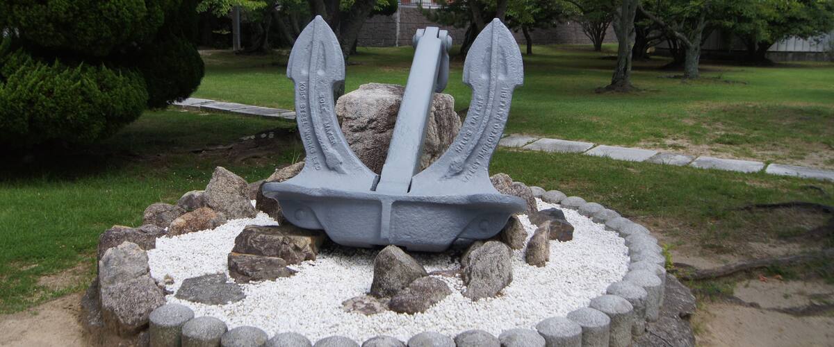 A stone sculpture of an anchor surrounded by rocks and gravel.