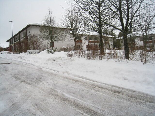 A snow-covered road with a building labeled 'Terrasse' and bare trees.