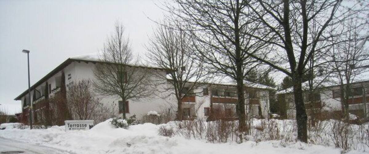 A snow-covered road with a building labeled 'Terrasse' and bare trees.