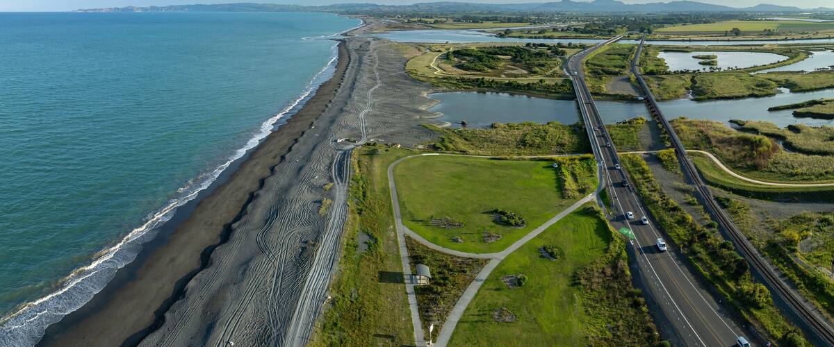 A coastal highway with a beach, a river, and a bridge.