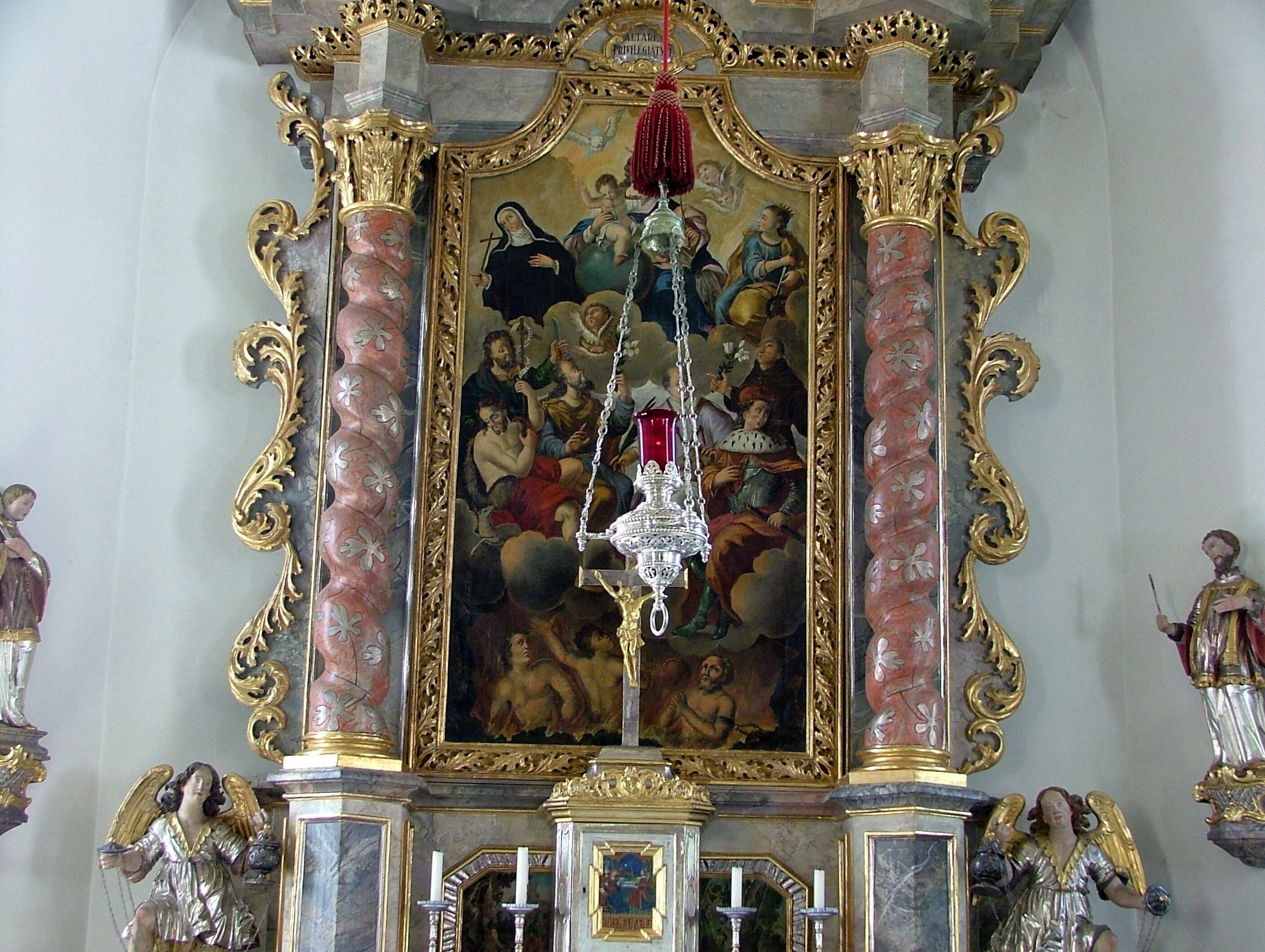 An ornate religious iconostasis with a central painting, gold detailing, and religious statues.