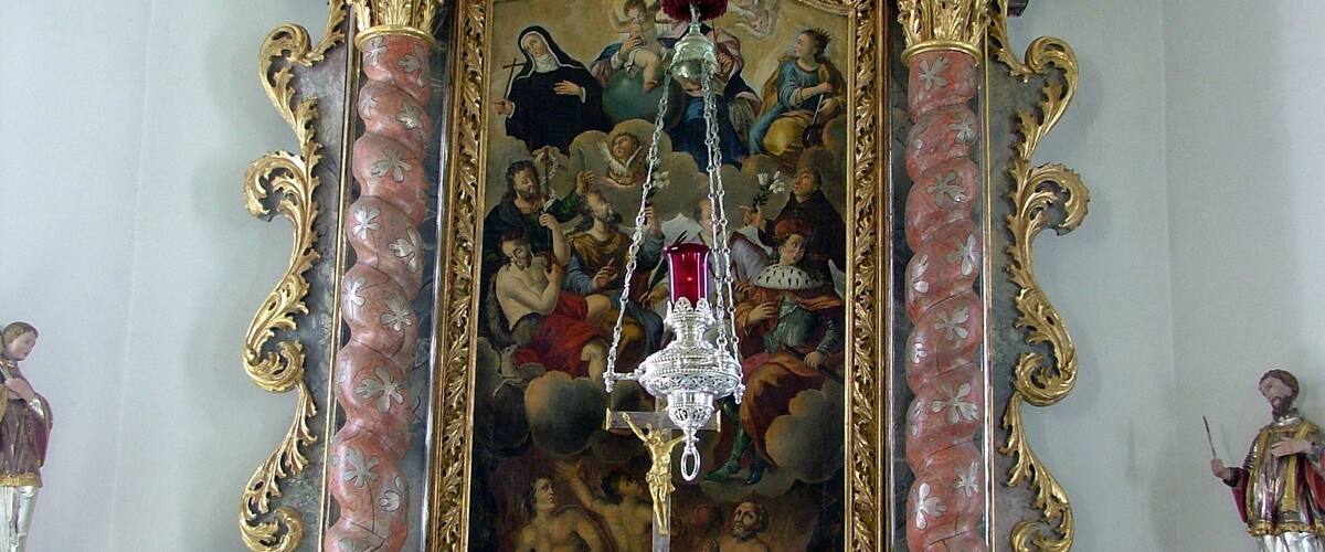 An ornate religious iconostasis with a central painting, gold detailing, and religious statues.