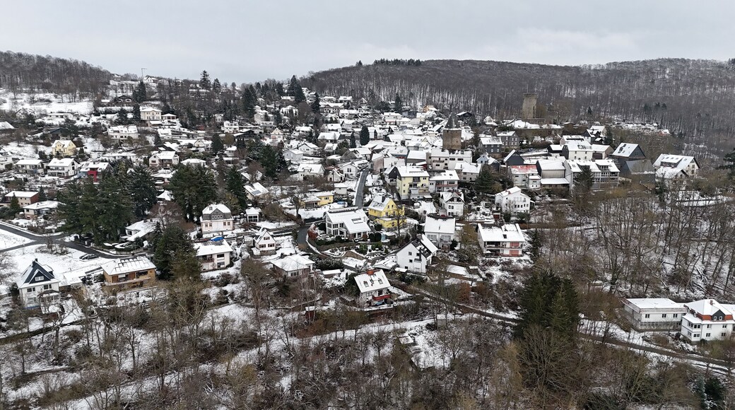 A snow-covered village with houses, a church, and a castle on a hill.