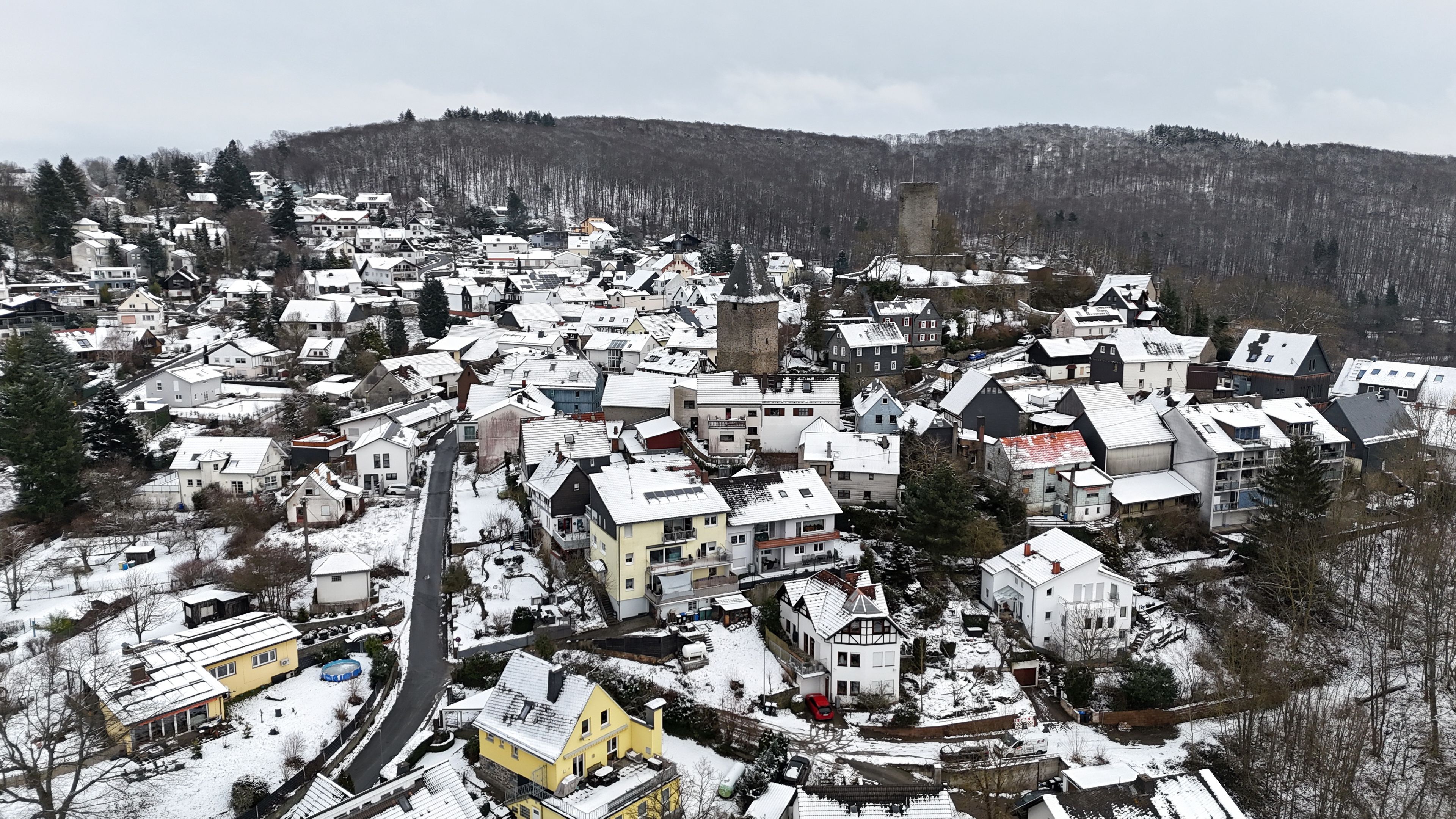 A snow-covered town with a mix of residential buildings and a prominent tower.