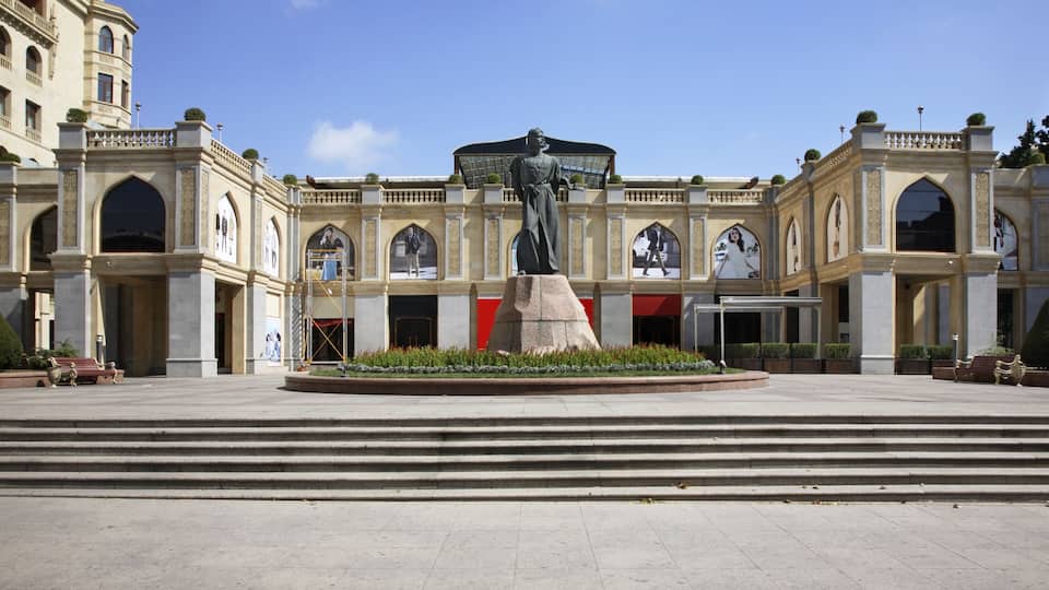 A grand building with a central statue, arched windows, and a large entrance.