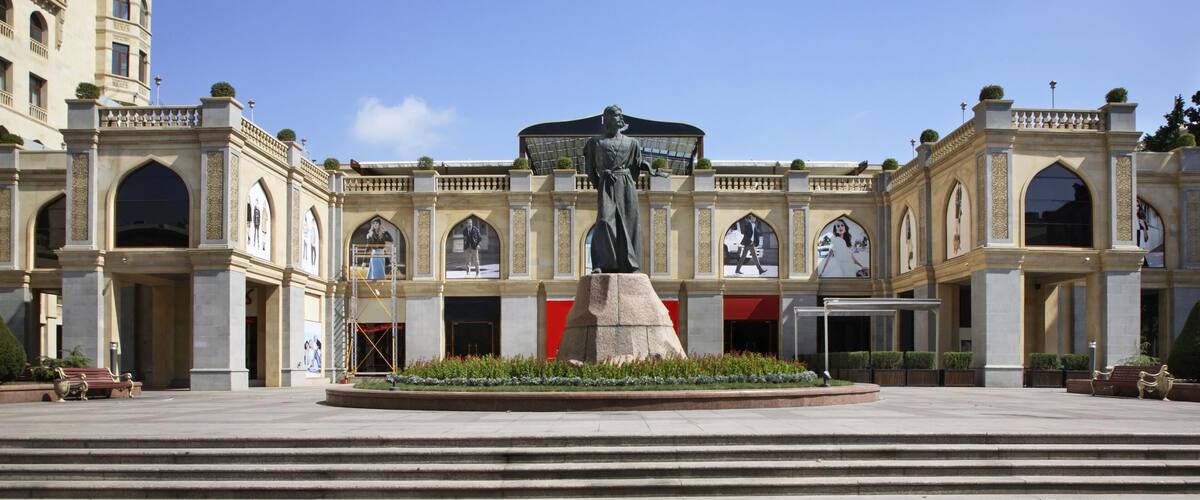 A grand building with a central statue, arched windows, and a large entrance.