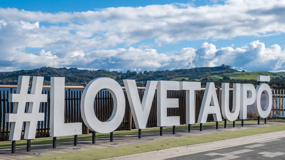 Hashtag Love Taupo sign in front of Lake Taupo in New Zealand.