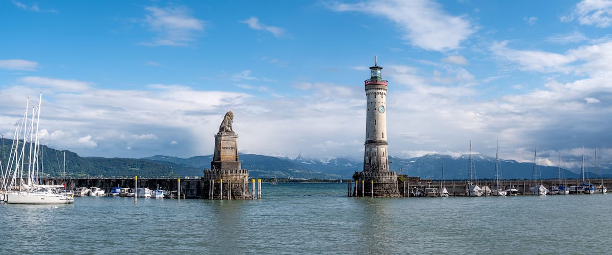 A coastal scene with two prominent lighthouses, a bridge, and a mountainous backdrop.