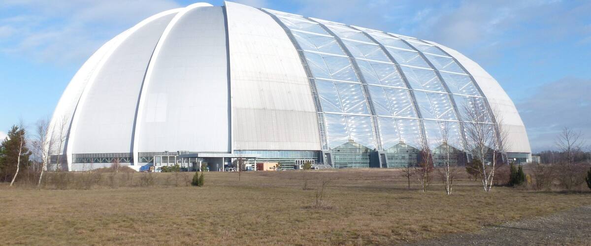A large, white, modern architectural structure with a curved roof and glass panels.