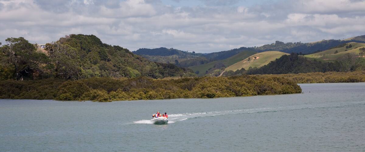 A boat on a lake surrounded by hills and trees.