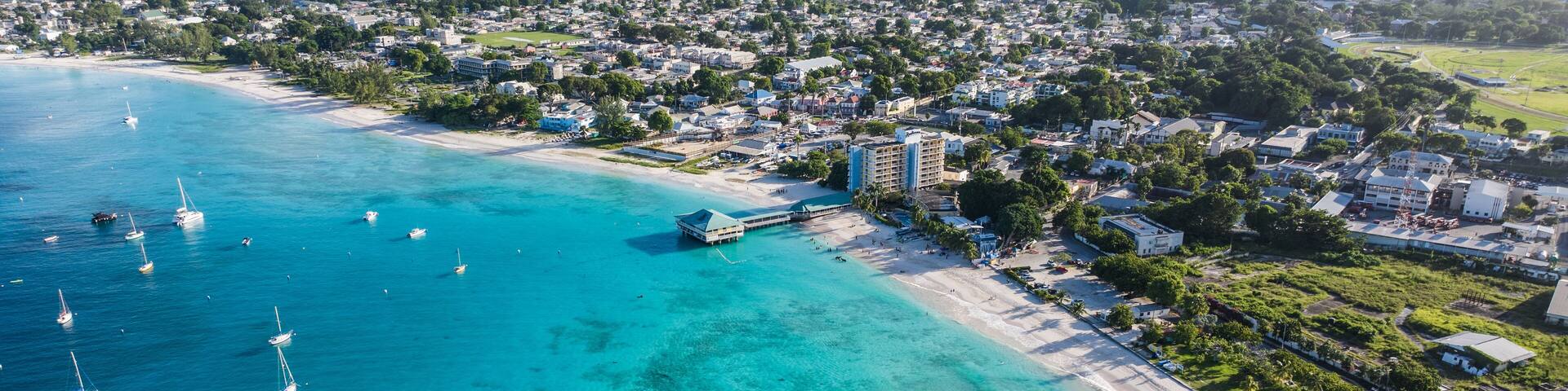 A coastal town with a beach, clear turquoise waters, and sailboats.