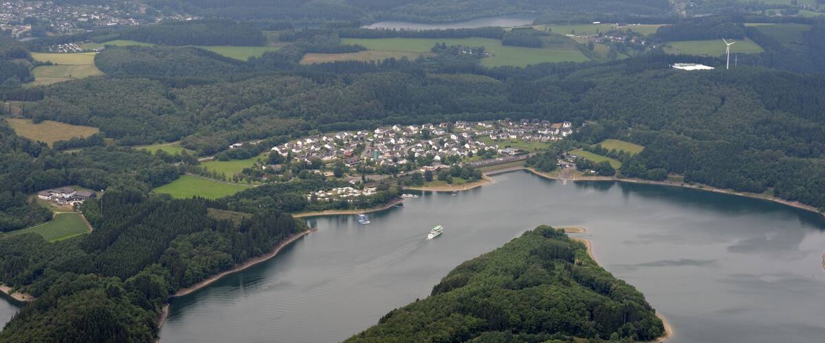 A coastal town surrounded by a lake, with wind turbines in the distance.