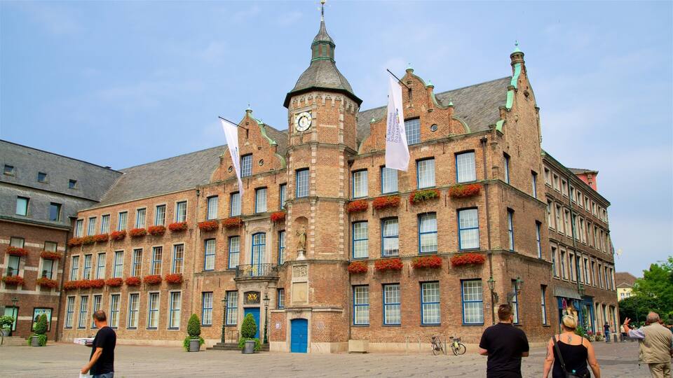 A historic building with a clock tower, red flower boxes, and flags.